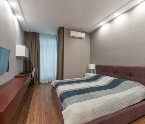 Elegant hotel room interior with a comfortable bed, modern furnishings, and a sleek design.